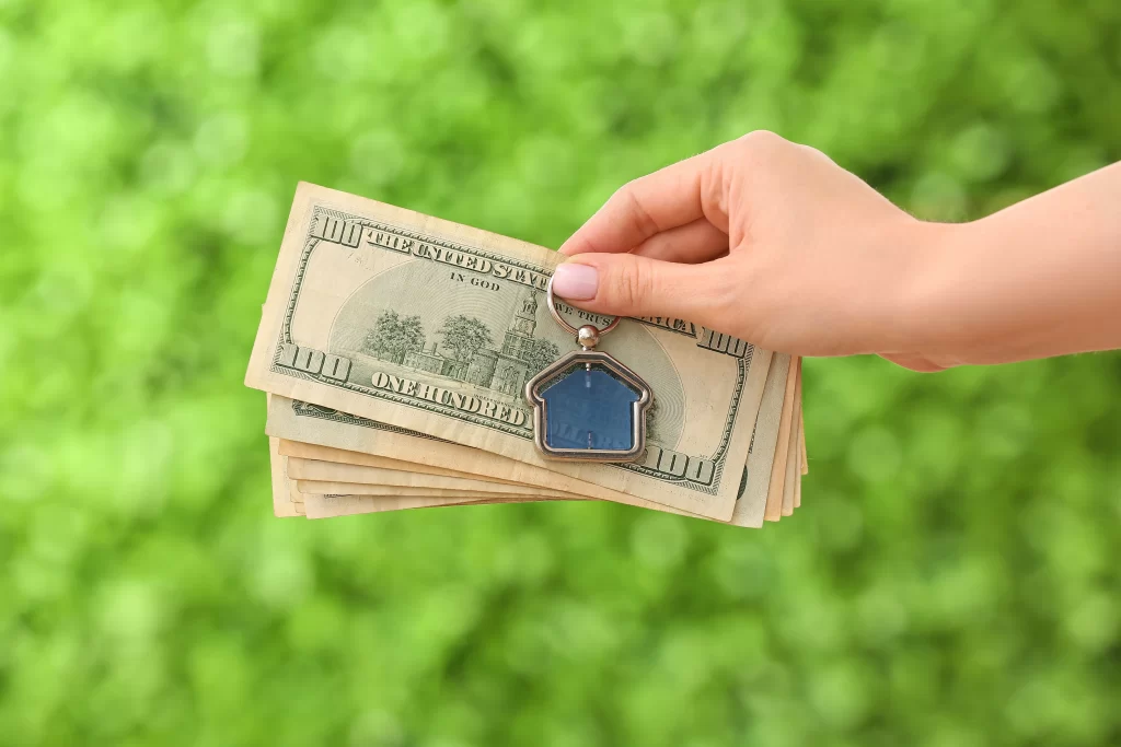 Hand holding dollars and house keyring