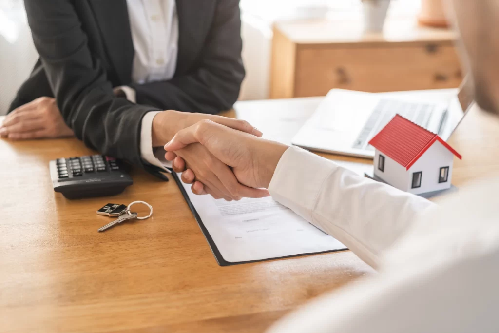 Handshake over house contract, keys on table