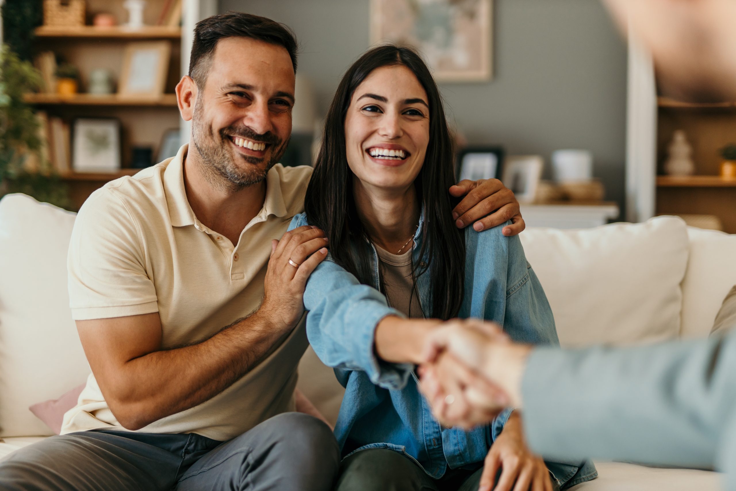 Smiling couple shaking hands at home